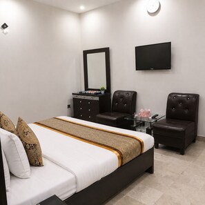 Une chambre à coucher moderne, équipée d’un lit, de deux fauteuils en cuir, d’une commode et d’un téléviseur à écran plat.