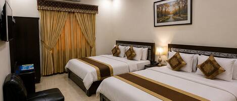A hotel room with two beds, a flat-screen TV, a ceiling fan, and a painting on the wall.