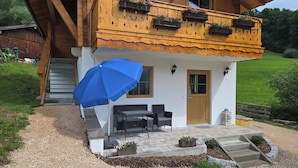 Eine Holzhütte mit Balkon, Sitzgelegenheit im Freien und Blumenkästen.