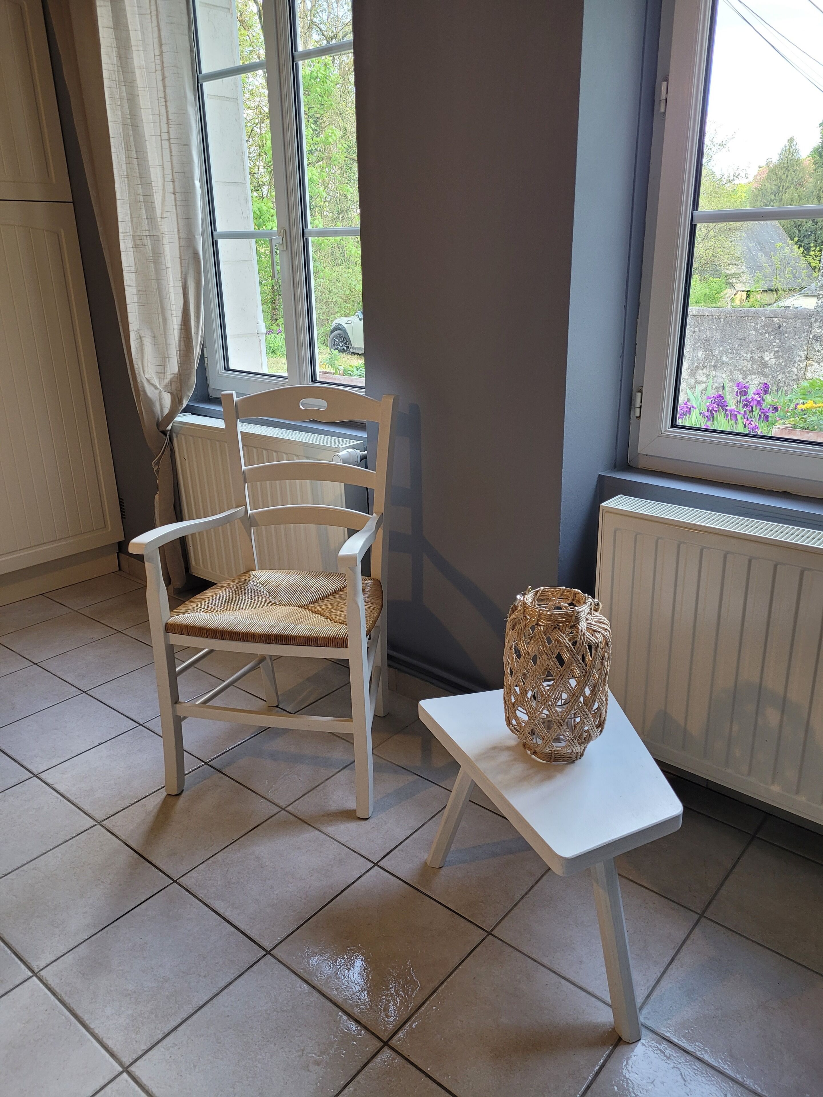 A room with a white chair, a small white table, and a wicker basket.