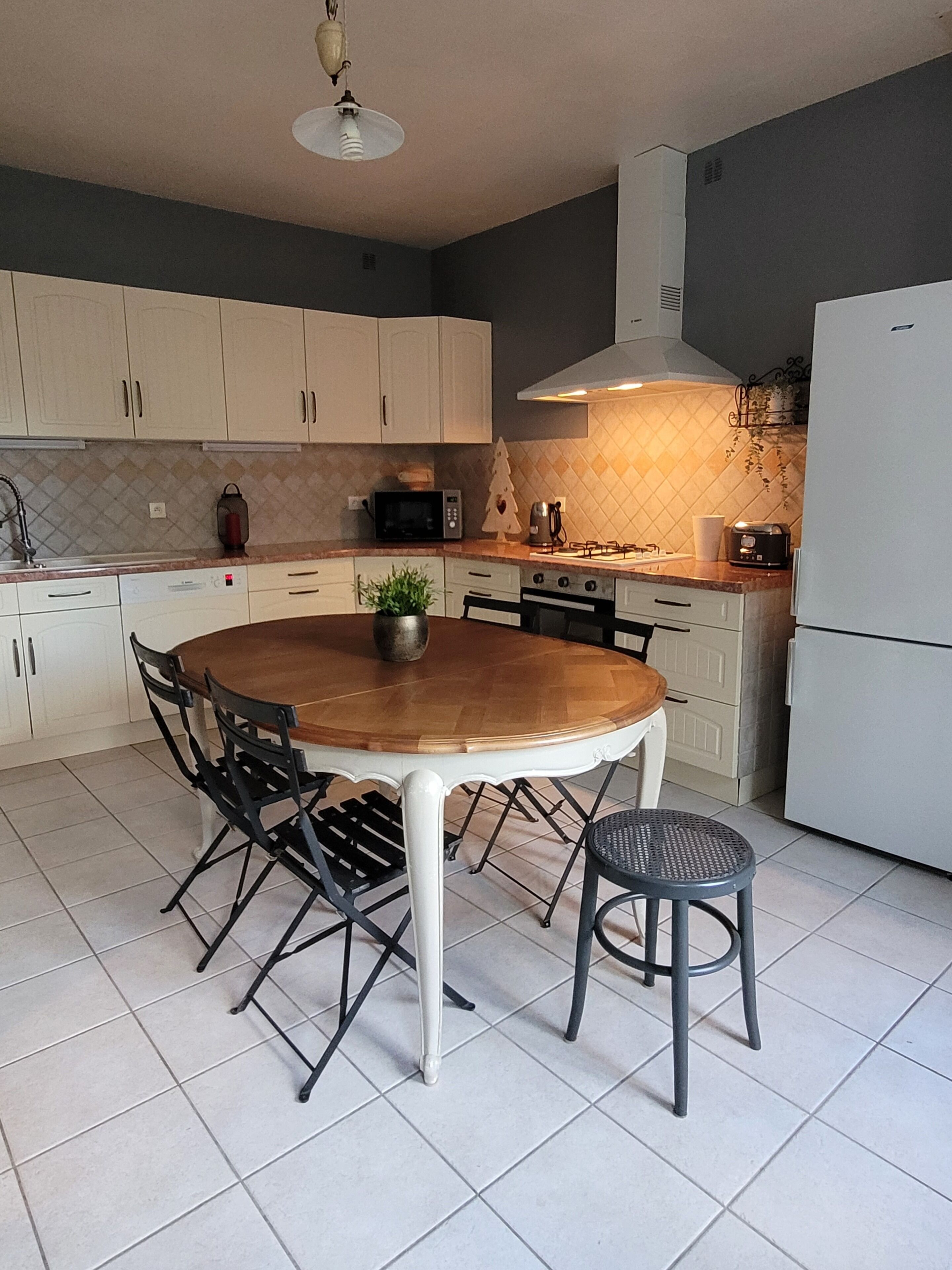 A modern kitchen with white cabinets, a wooden dining table, and black chairs.