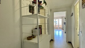 A hallway with a white shelving unit, a door leading to a balcony, and a tiled floor. - JORA 3A (Estartit)