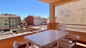 A balcony with a table and chairs, overlooking a residential area with buildings. - JORA 3A (Estartit)