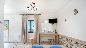 Une chambre à coucher comprenant un lit, un bureau, une chaise, un téléviseur et une fenêtre avec des rideaux.