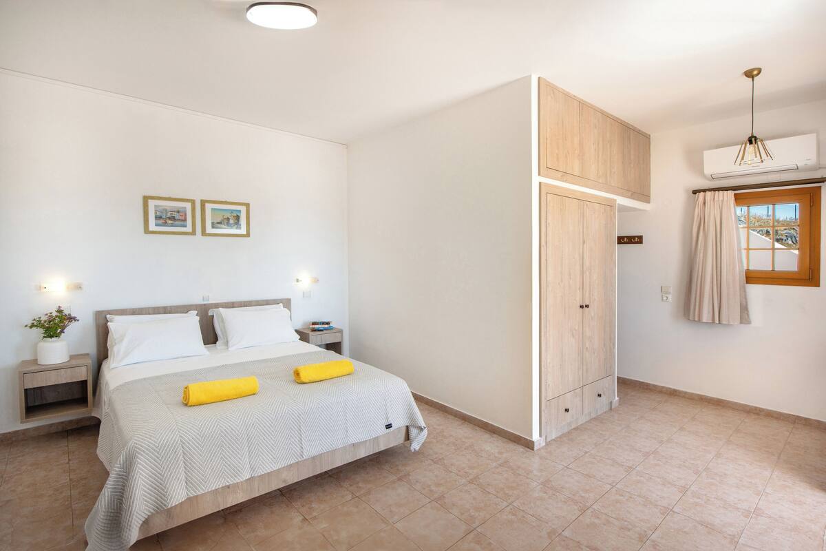 A bedroom with a bed, nightstands, a potted plant, and a wardrobe.