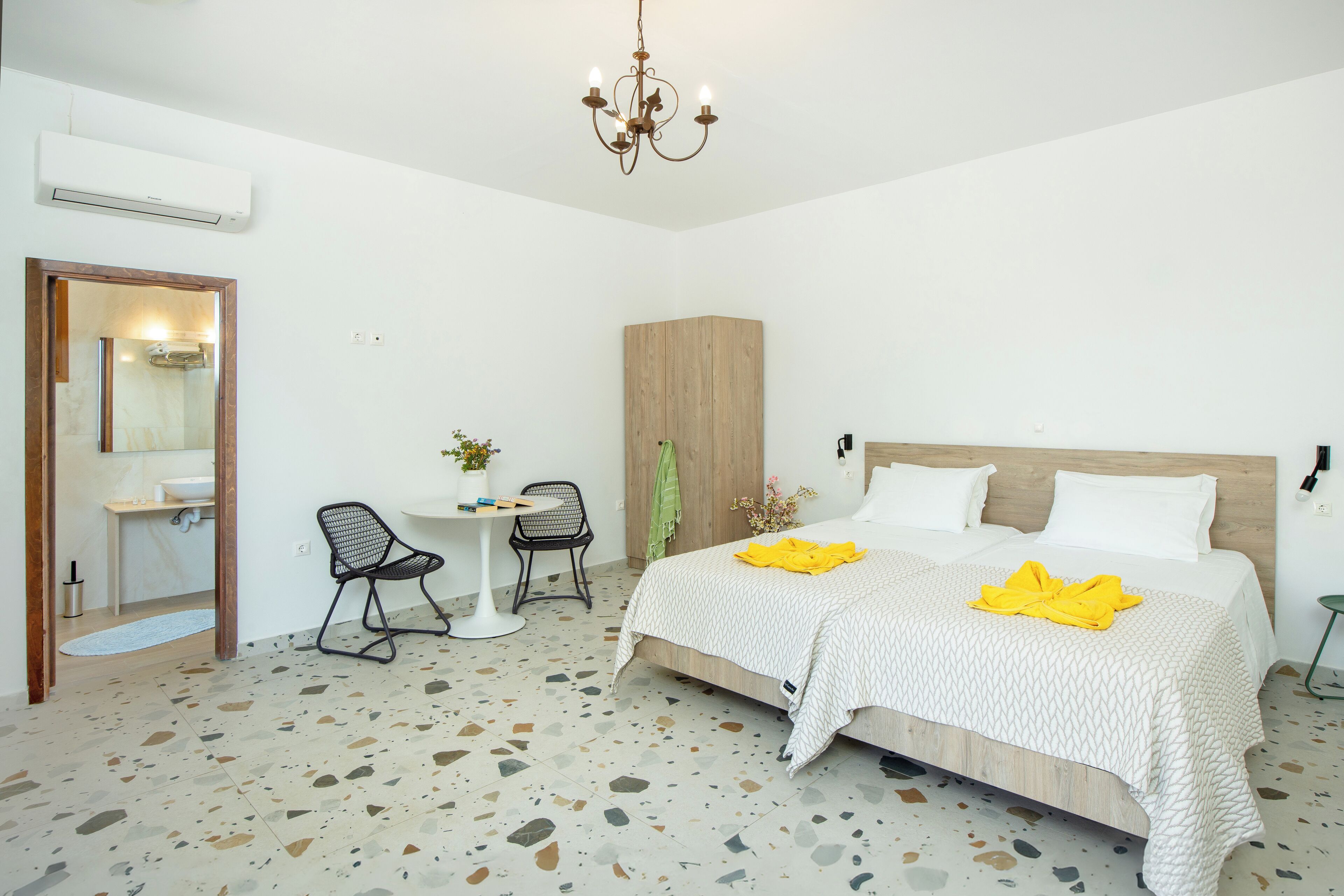 Ein Schlafzimmer mit einem Bett, einem Sessel, einem kleinen Tisch, einem Spiegel und einem Holzschrank.