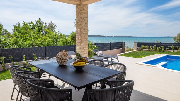 A covered outdoor area with a pool, dining table, and chairs. - Villa Eleni ZadarVillas (Ljubač)