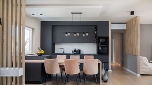 A modern kitchen with a central island, black cabinets, and a dining area with four chairs. - Villa Eleni ZadarVillas (Ljubač)