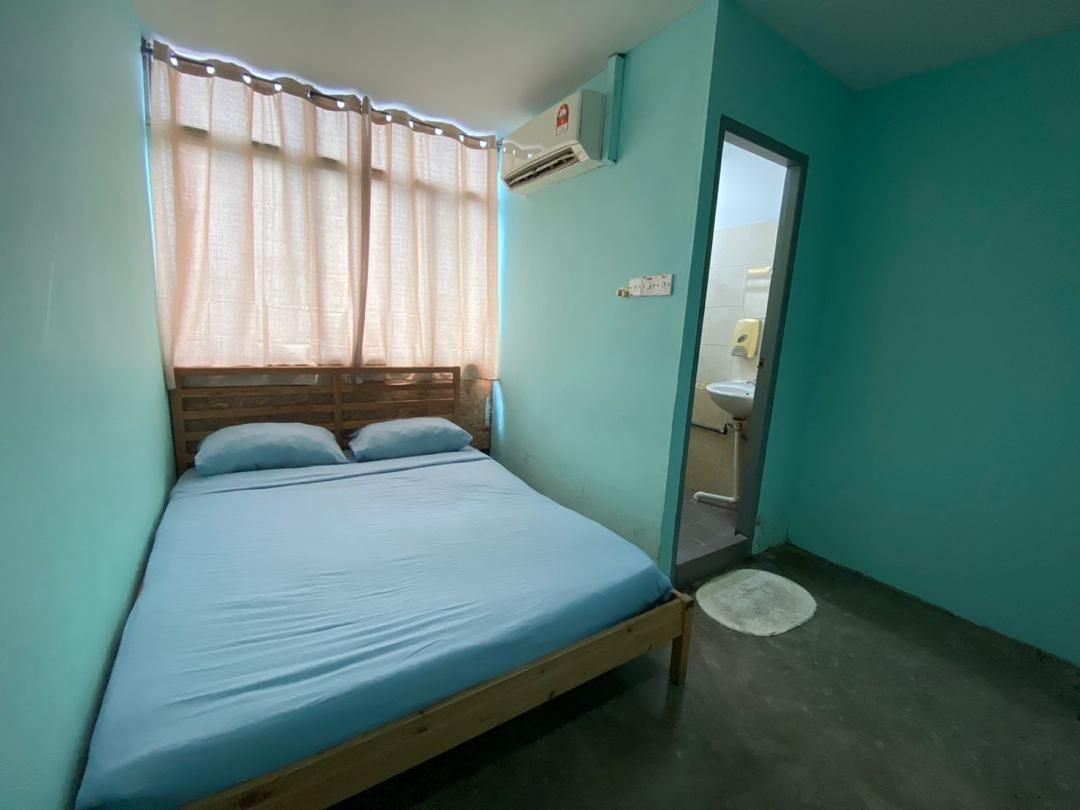 Une chambre avec un lit, une fenêtre avec des rideaux, un appareil de climatisation et une porte donnant sur une salle de bain.