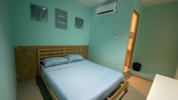 A single bed with a wooden headboard, a small bedside table, and a wall-mounted air conditioning unit.