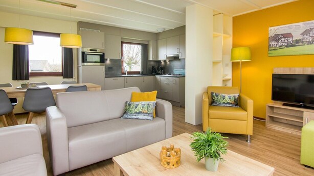 Ein modernes Wohnzimmer mit einer Couch, Sesseln, einem Couchtisch und einem Fernseher.