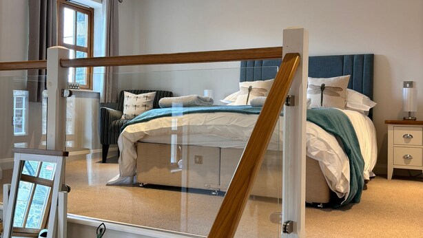 A bedroom with a bed, nightstands, a dresser, and a staircase.