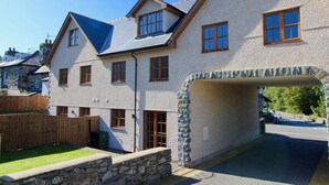A two-story house with a stone facade, a sloped roof, and a stone archway entrance.