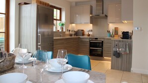 A modern kitchen with a built-in oven, a refrigerator, and a dining area with a table set for two.