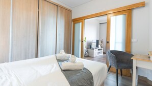 A hotel room with a bed, a desk, a chair, and a sliding door leading to a bathroom.