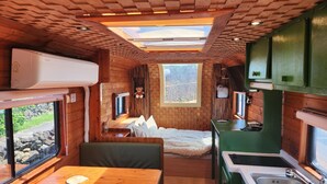 A compact cabin with a wooden interior, a small kitchenette, a bed, and a dining area. - Jeju Pyeongdae 41street Pension (Jeju City)