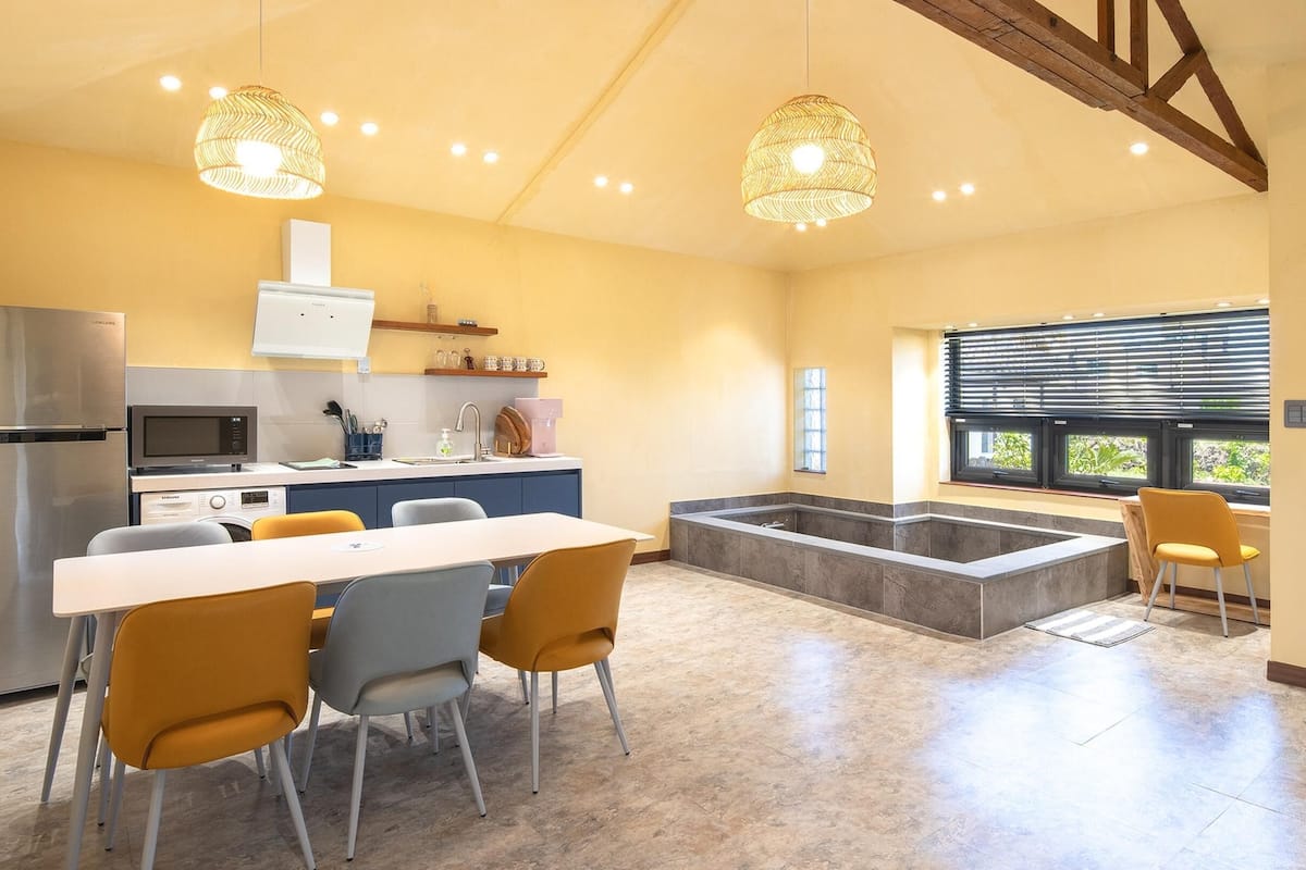 A modern kitchen with a dining area, built-in appliances, and a large window.