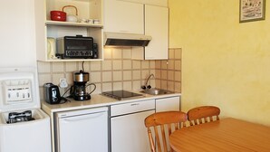 A compact kitchen with a coffee maker, toaster, and a small refrigerator. There is a dining table with two chairs and a single chair visible. - LE CAPITOLE, Sea view, Studio cabin 27m2 waterfront, 2 adults, 2 children, air conditioning and garage (Fréjus)
