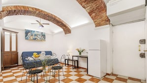 Ein Essbereich mit Schachbrettmuster-Boden, einem Tisch mit Stühlen, einem Deckenventilator und einem Bild an der Wand.