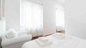 Une chambre d’hôtel avec un lit, une chaise et une fenêtre avec des rideaux.