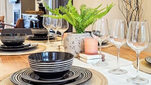Une table à manger dressée avec des bols rayés noirs et blancs, des verres à vin transparents et une bougie.