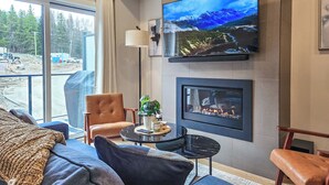 Un salon moderne doté d’un grand téléviseur, d’une cheminée et de sièges confortables.