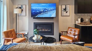 Un salon moderne doté d’un téléviseur à écran plat, d’une cheminée, de fauteuils en cuir et d’un coin salon confortable.