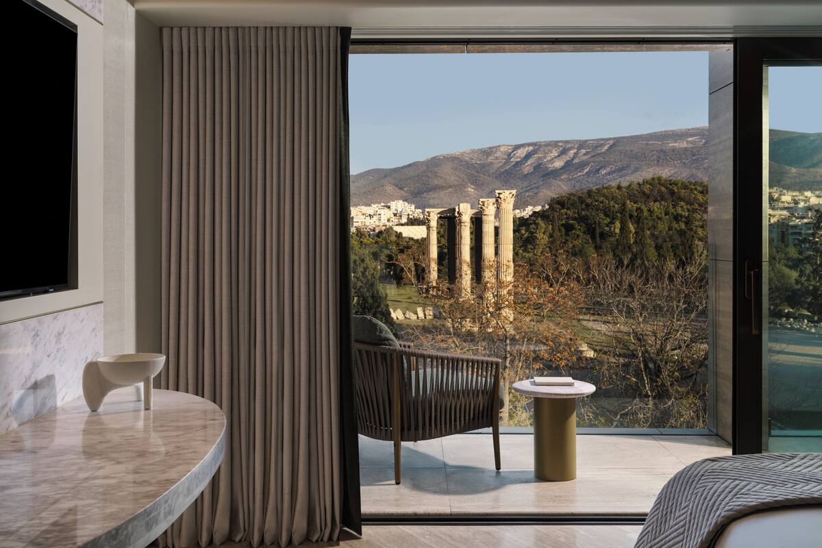 A modern room with a large window, a marble table, a chair, and a small round table.