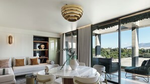 Een moderne woonkamer met een ronde marmeren tafel, witte banken en een groot raam met uitzicht op de stad.