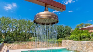 A pool with a water feature overhead, surrounded by a stone wall and greenery. - Flateli El Racó de Diana (Sant Jordi Desvalls)