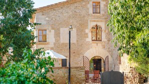 A stone building with a rustic facade, a gated entrance, and outdoor seating. - Flateli El Racó de Diana (Sant Jordi Desvalls)