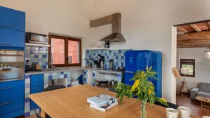 Een keuken met blauwe kastjes, een houten tafel en een vaas met bloemen.