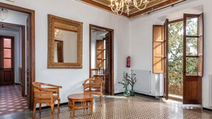 Een ruime kamer met een kamerbreed vloerkleed, houten meubels, een grote spiegel en een kroonluchter.