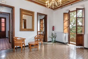 Une pièce spacieuse dotée d’un sol à motifs, de meubles en bois, d’un grand miroir et offrant une vue sur l’extérieur grâce à une porte ouverte.