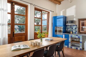Une cuisine avec une table en bois, des chaises, un livre et un vase rempli de fleurs.