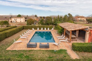 A rectangular swimming pool with lounge chairs and a barbecue area. - Flateli. Casa Indiana (Bordils)