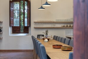 A dining area with a long wooden table, blue upholstered chairs, and hanging pendant lights.