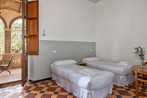 A room with two single beds, a wooden table, and a chair.