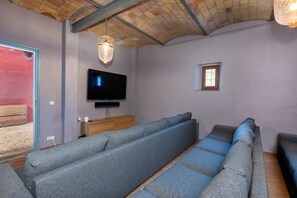 A living room with a large gray sofa set, a flat-screen TV mounted on the wall, and a wooden cabinet below.