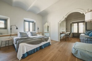 Un dormitorio con una cama grande, un escritorio y una silla. Hay ventanas y un arco de entrada.