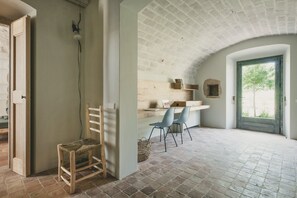 Une pièce rustique avec un sol en briques, un banc en bois et un bureau avec deux chaises.