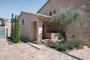 A courtyard with a tiled floor, a stone wall, and a tree.
