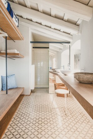 Une salle de bain moderne avec un meuble-lavabo en bois, un grand panier tressé et un carrelage à motifs.