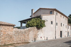 Un bâtiment en pierre avec un toit en tuiles, un petit balcon et un arbre fruitier.