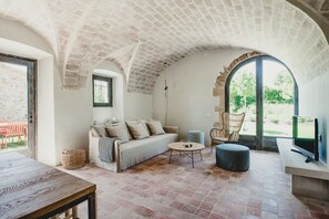 A cozy living room with a brick ceiling, a sofa, a coffee table, and a television. - Flateli. Casa Oliver (Cervià de ter)