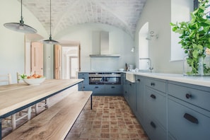 Une cuisine avec une table en bois, un saladier de fruits et une plante.
