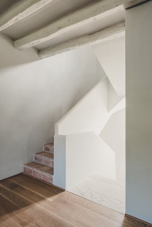 A staircase with white walls and wooden flooring.