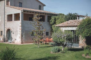 A two-story building with a balcony, outdoor seating, and a garden area.