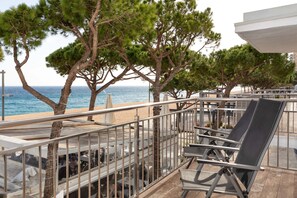A terrace with outdoor seating, overlooking a beach and the sea.