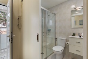 Une salle de bain moderne avec une douche à parois de verre, des toilettes et un meuble-lavabo avec des tiroirs.
